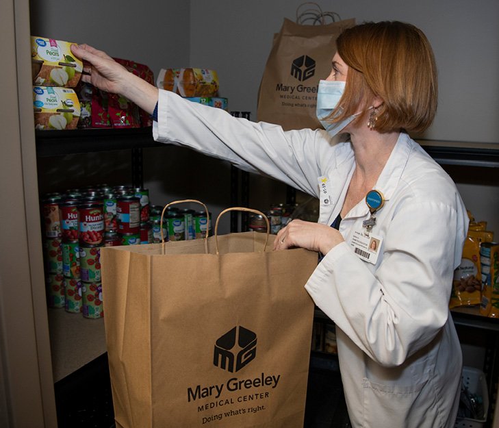 Sarah Haveman, diabetes educator, loads a bag with healthy foods for a Nourish client. The program is supported by the Mary Greeley Foundation.