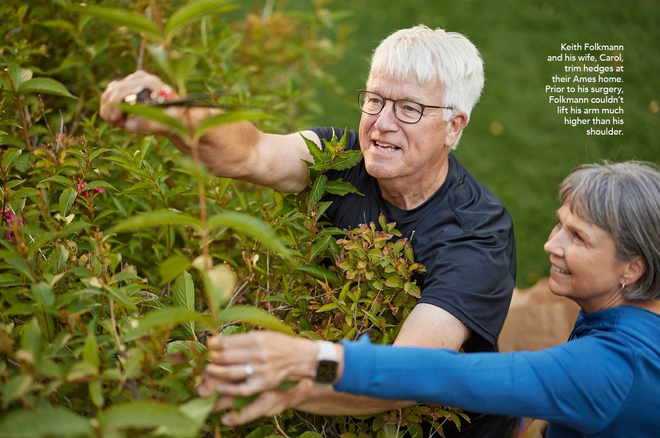 Keith Folkmann and his wife, Carol, trim hedges at their Ames home. Prior to his surgery, Folkmann couldn’t lift his arm much higher than his shoulder.