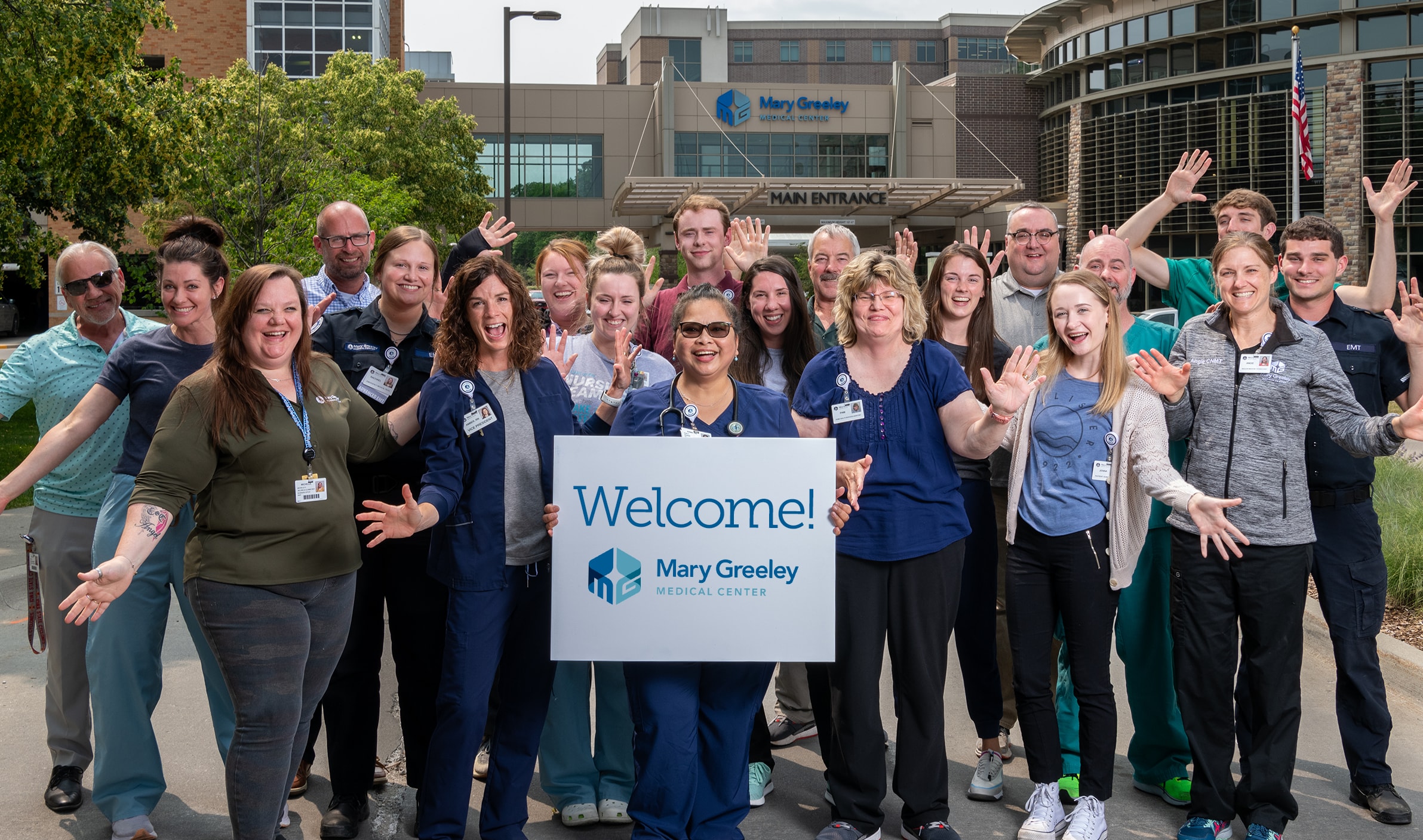 A group of Mary Greeley Employees in front of the hospital holding a Welcome sign.