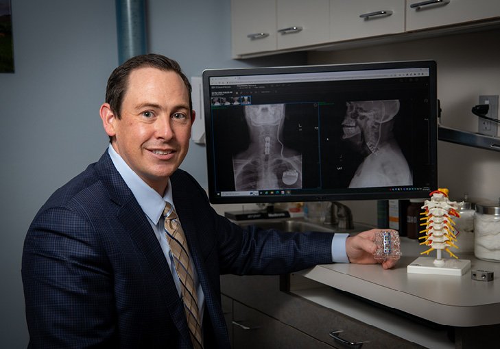 Dr Jonathon Geisinger poses in his office with a replica of the implant he used for Keith Folkmann.