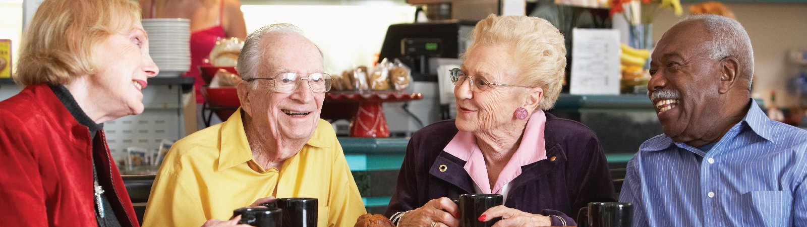 Seniors gathered at a table enjoying coffee together.